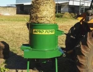 Triturador de fardos Agroforn acoplado ao trator processando um fardo cilíndrico inteiro para alimentação animal.