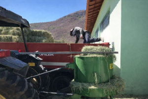 Operador abastecendo Triturador AF10 a cardan acoplado ao trator no campo, ilustrando a mobilidade do equipamento.