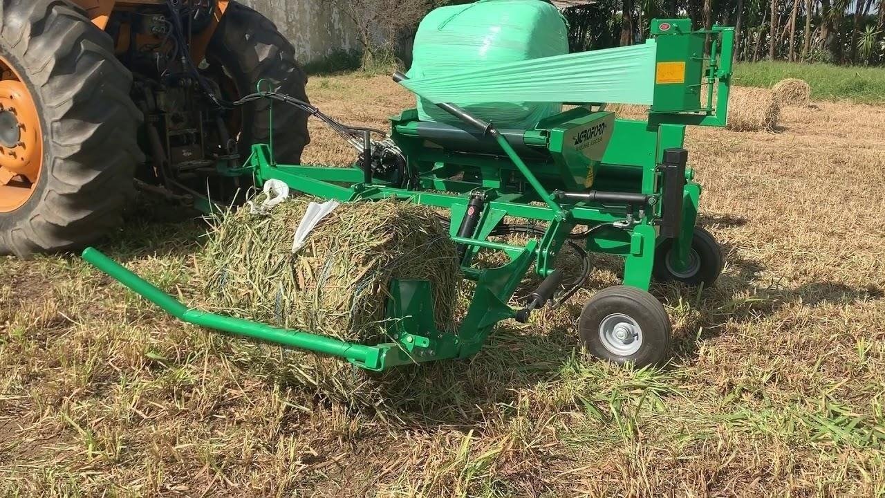 Máquina agrícola em operação no campo, com estrutura robusta manipulando feno; imagem ilustra a qualidade e eficiência dos equipamentos da Agroforn no agronegócio.