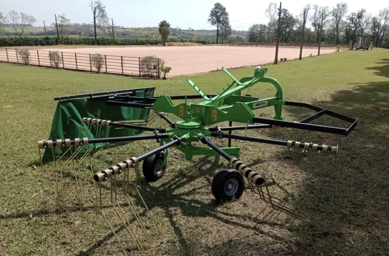 Ancinho enleirador Agroforn AF320/8 em operação no campo, acoplado ao trator, formando leiras uniformes de feno com forragem limpa e bem distribuída para enfardamento.